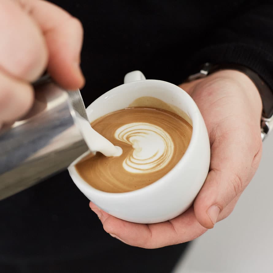 Latte art being poured at Qurbah House of Coffee